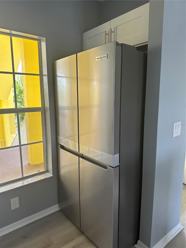 interior space with white cabinets, stainless steel refrigerator, and light hardwood / wood-style floors