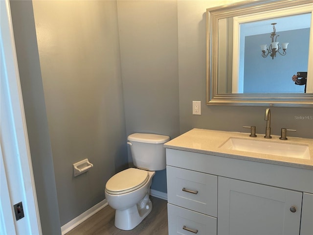 bathroom featuring vanity, hardwood / wood-style floors, a notable chandelier, and toilet