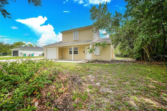 view of property featuring a garage, covered porch, and a front lawn