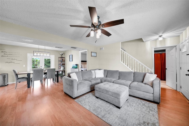 living room with hardwood / wood-style flooring, ceiling fan, and a textured ceiling