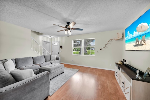 living room featuring ceiling fan, wood-type flooring, and a textured ceiling