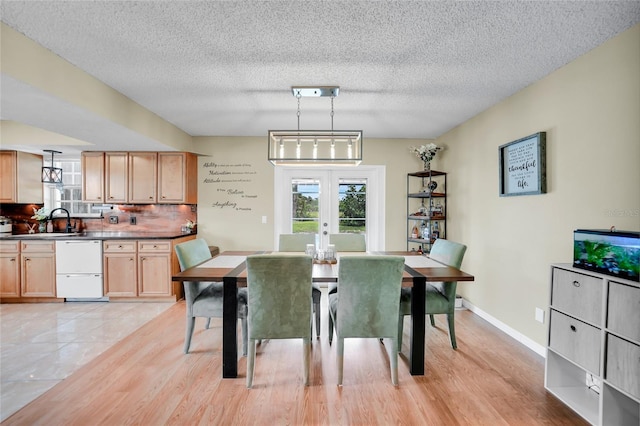 dining room with french doors, sink, light hardwood / wood-style flooring, and a textured ceiling