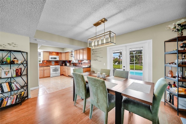 dining area featuring sink, light hardwood / wood-style floors, french doors, and a textured ceiling