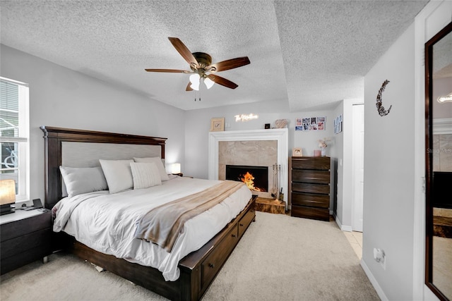 carpeted bedroom with a tiled fireplace, ceiling fan, and a textured ceiling