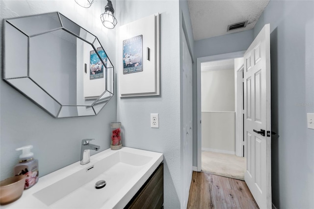 bathroom with vanity, hardwood / wood-style floors, and a textured ceiling