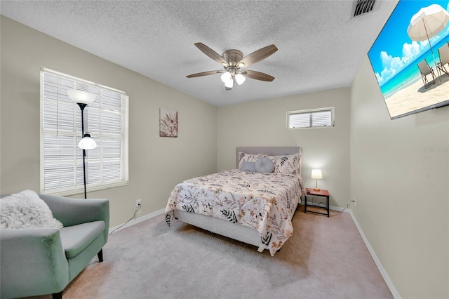 bedroom with ceiling fan, light carpet, and a textured ceiling