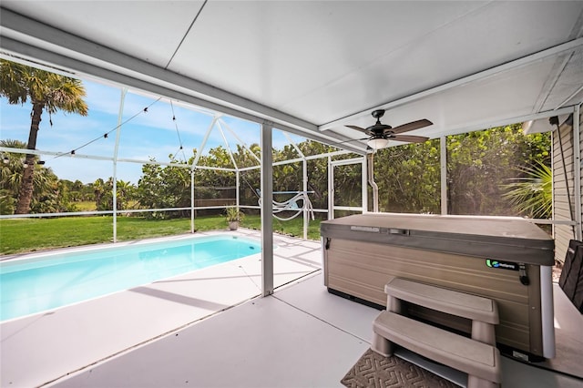 view of swimming pool featuring a lawn, ceiling fan, a patio, glass enclosure, and a hot tub