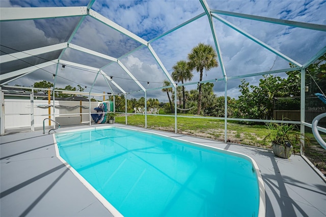 view of swimming pool with a lawn, glass enclosure, and a patio area