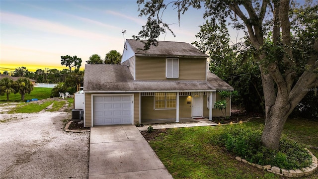 view of front of home featuring a garage, a lawn, and central air condition unit