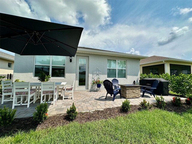 rear view of property featuring a fire pit and a patio