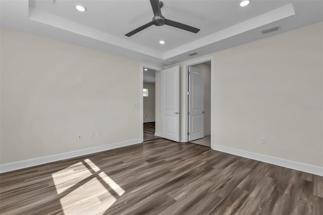 spare room featuring ceiling fan, dark hardwood / wood-style floors, and a raised ceiling