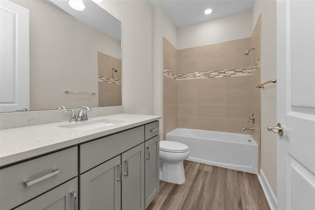 full bathroom featuring tiled shower / bath combo, hardwood / wood-style floors, toilet, and vanity