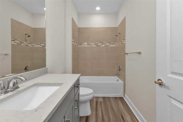 full bathroom with vanity, hardwood / wood-style flooring, tiled shower / bath, and toilet