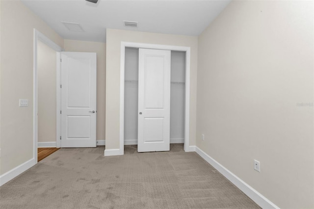 unfurnished bedroom featuring light colored carpet and a closet