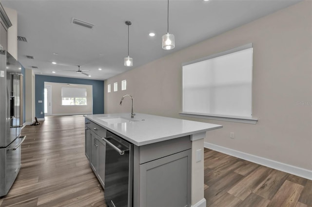 kitchen featuring sink, gray cabinets, a center island with sink, and appliances with stainless steel finishes