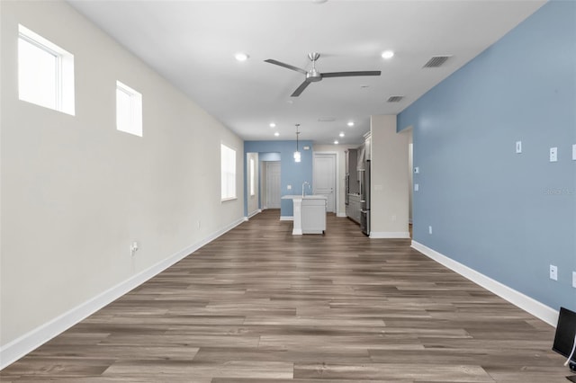 unfurnished living room with sink, ceiling fan, and hardwood / wood-style floors