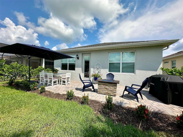 rear view of property featuring a patio area and a fire pit