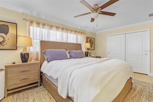 bedroom with ceiling fan, a closet, light tile patterned floors, and ornamental molding