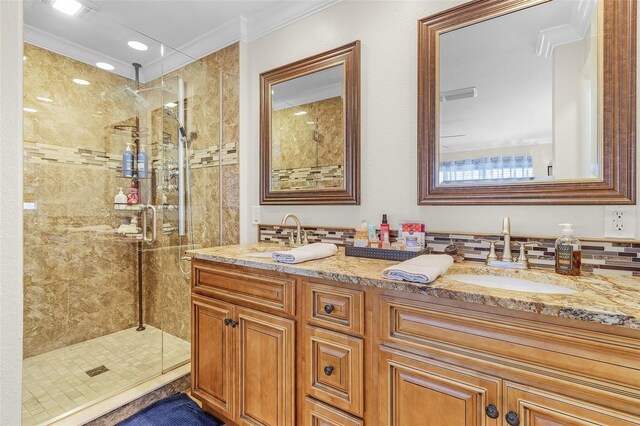 bathroom featuring backsplash, a shower with shower door, crown molding, and dual bowl vanity