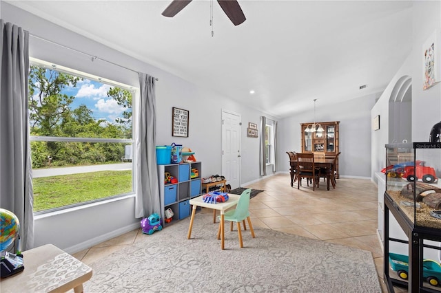 rec room with ceiling fan, light tile patterned floors, and vaulted ceiling