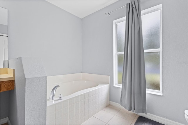 bathroom featuring tile patterned floors, toilet, and tiled bath