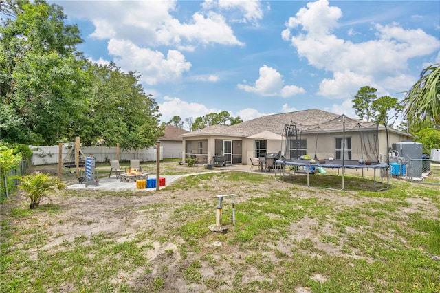 back of property featuring a patio, a trampoline, and a fire pit