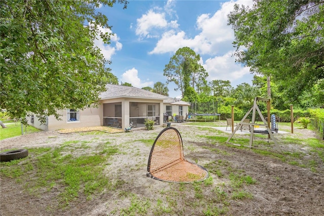 exterior space with a playground, a sunroom, and a trampoline