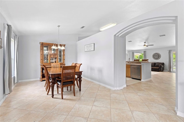 dining space with ceiling fan with notable chandelier and light tile patterned floors