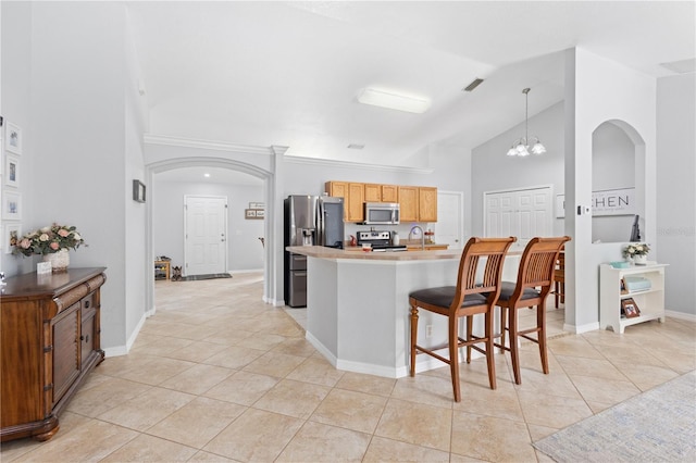 kitchen featuring appliances with stainless steel finishes, light tile patterned floors, a chandelier, hanging light fixtures, and lofted ceiling