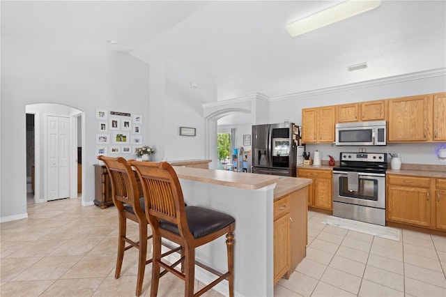 kitchen with a breakfast bar, light tile patterned floors, a center island, and stainless steel appliances