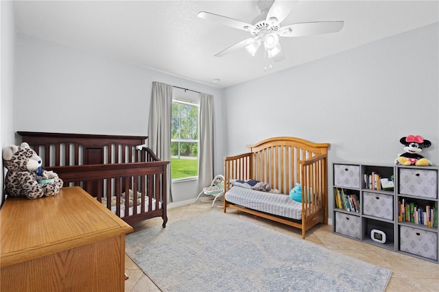 tiled bedroom featuring ceiling fan and a crib