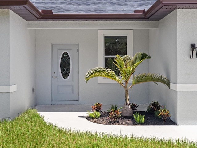 property entrance with stucco siding and roof with shingles