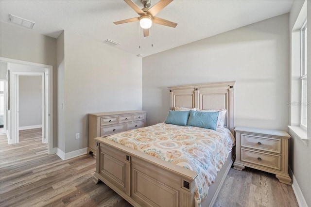 bedroom featuring a ceiling fan, light wood-type flooring, visible vents, and baseboards