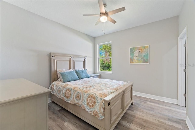 bedroom with light wood-type flooring, ceiling fan, and baseboards