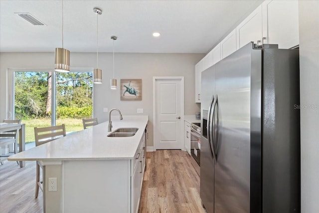 kitchen featuring stainless steel appliances, a sink, visible vents, and white cabinets