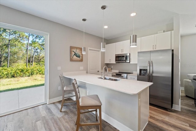 kitchen featuring decorative light fixtures, light countertops, appliances with stainless steel finishes, white cabinets, and a sink