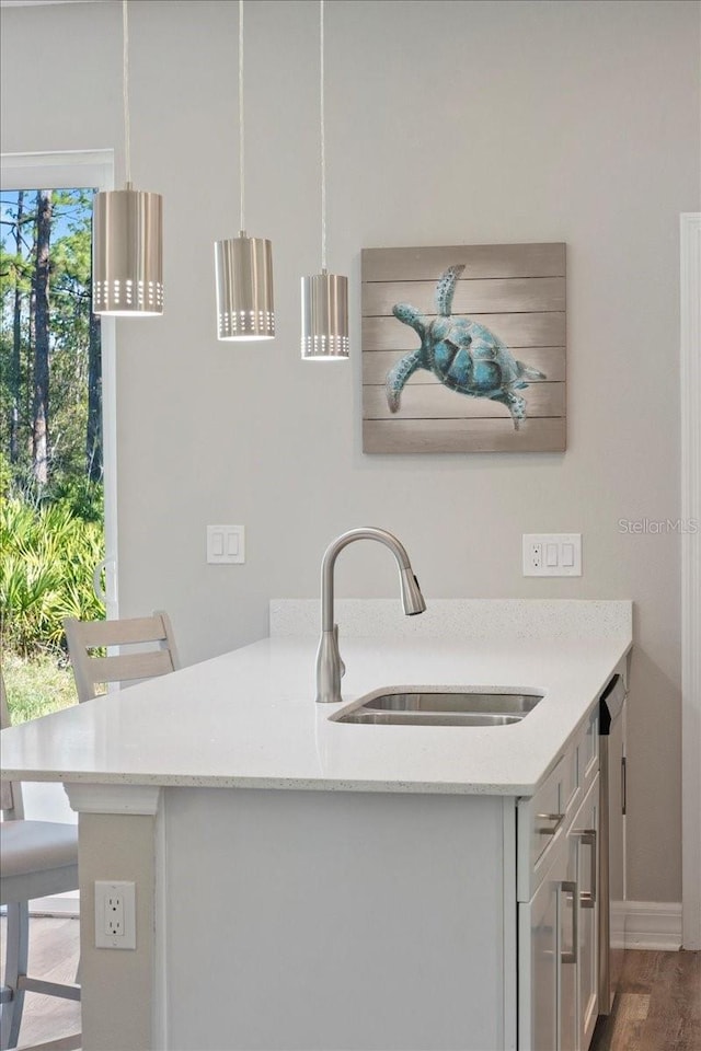 kitchen with a breakfast bar area, hanging light fixtures, light stone countertops, a peninsula, and a sink