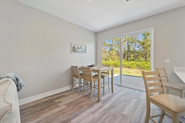 dining space featuring light wood finished floors and baseboards