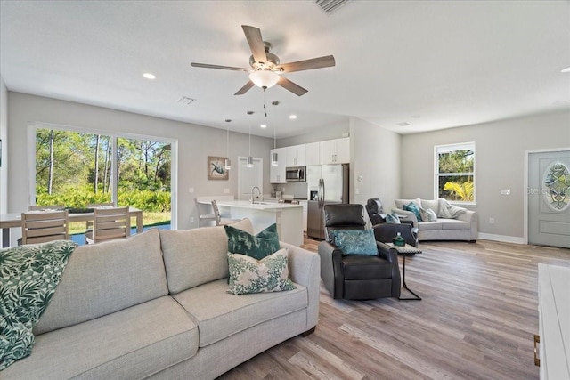 living area with light wood-type flooring, baseboards, and recessed lighting