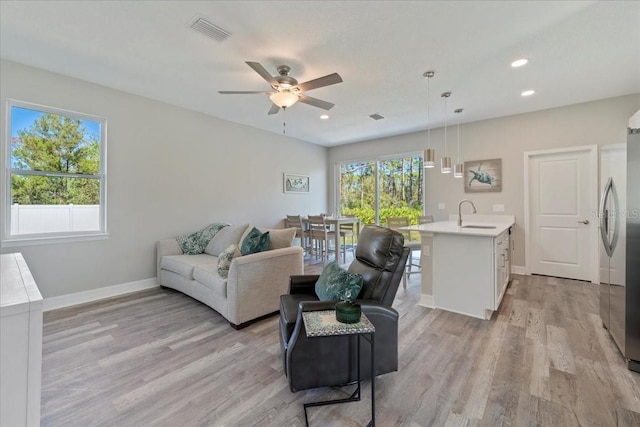 living area with light wood finished floors, plenty of natural light, visible vents, and baseboards