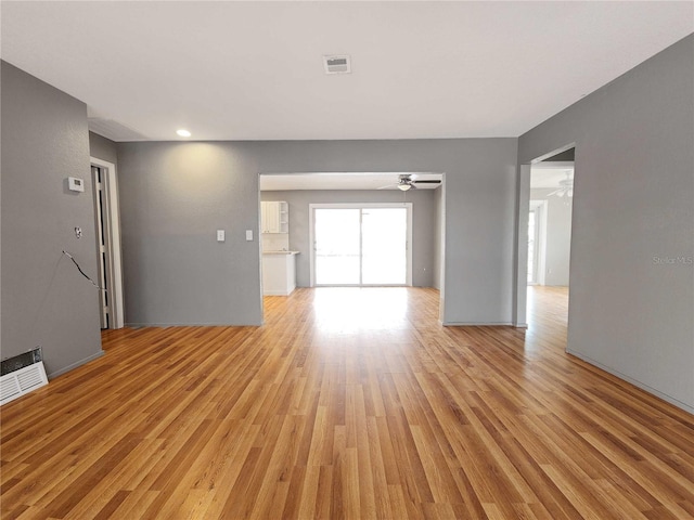 unfurnished living room with visible vents, ceiling fan, baseboards, and light wood-style floors