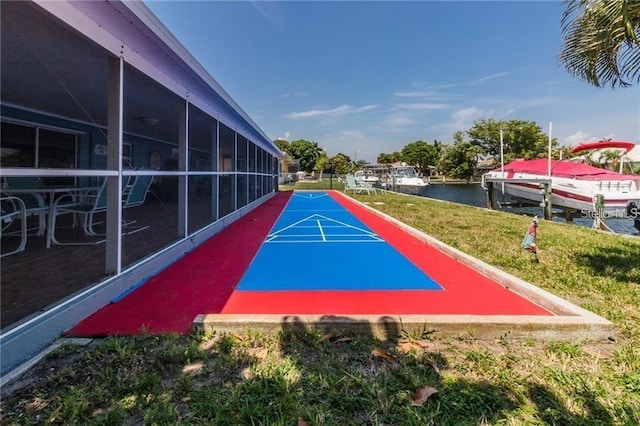 view of property's community with a lawn, shuffleboard, a boat dock, and a water view