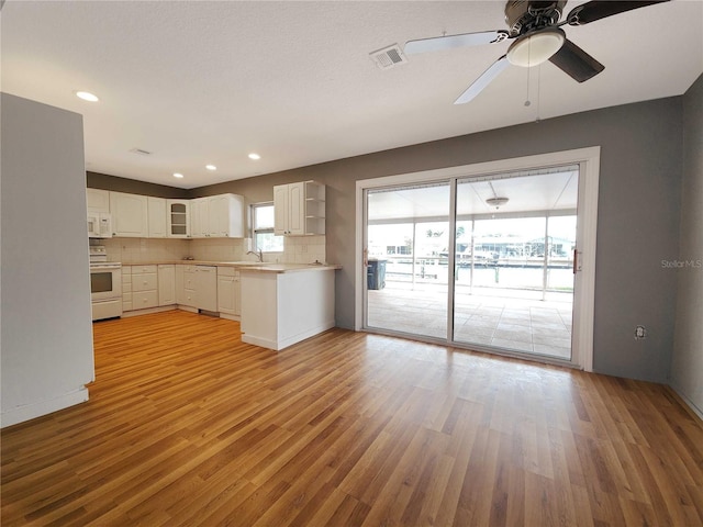 kitchen featuring white appliances, a sink, white cabinets, light wood-style floors, and tasteful backsplash