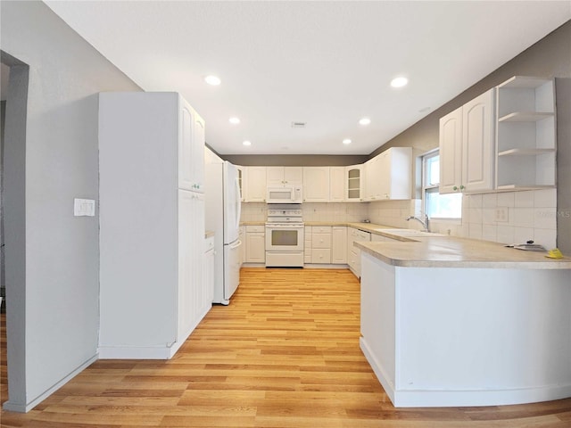 kitchen featuring glass insert cabinets, decorative backsplash, light wood-style floors, white appliances, and a sink