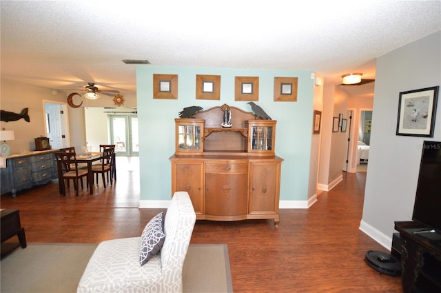 living room with a textured ceiling, dark hardwood / wood-style flooring, and ceiling fan