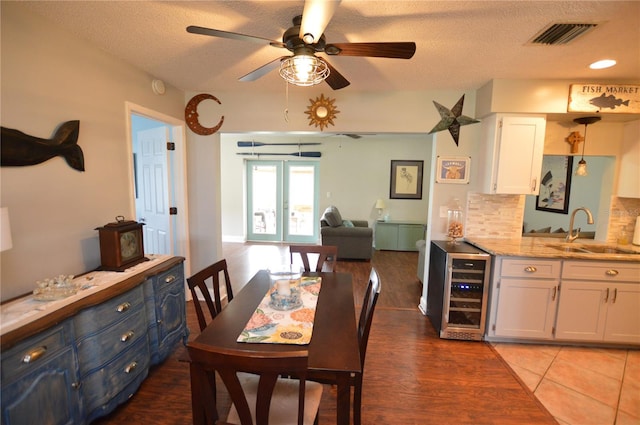 dining area with a textured ceiling, ceiling fan, sink, and beverage cooler