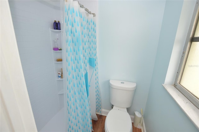 bathroom with hardwood / wood-style floors, a shower with curtain, and toilet