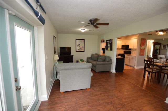 living room featuring ceiling fan, a textured ceiling, and dark wood-type flooring