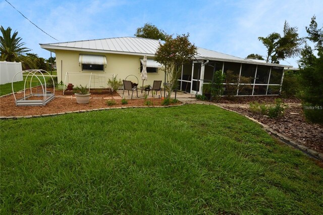 rear view of house featuring a sunroom, a yard, and a patio