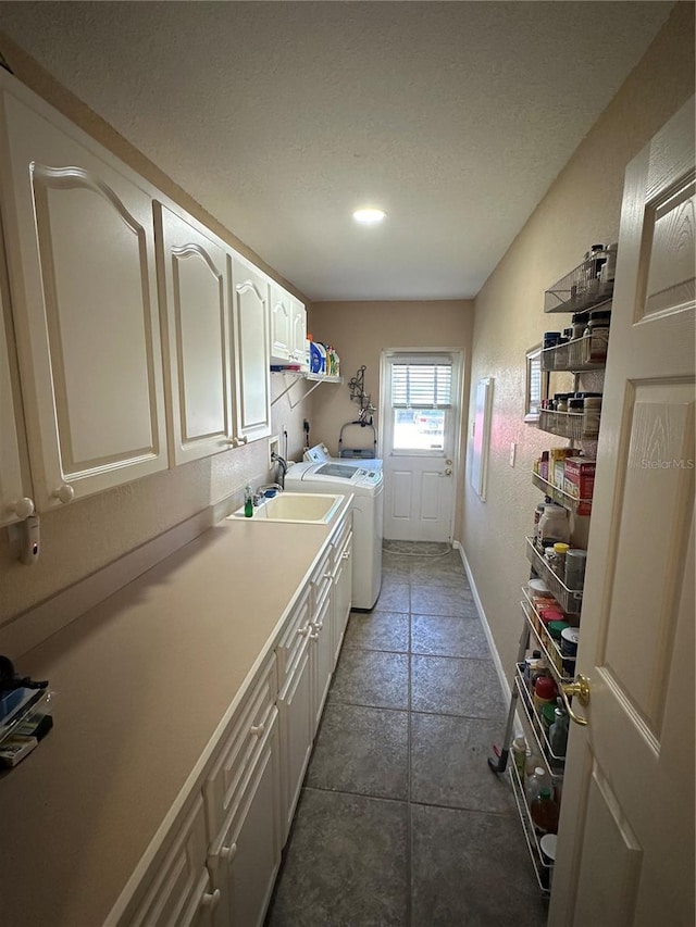 laundry room with tile patterned flooring, a textured ceiling, washing machine and dryer, cabinets, and sink